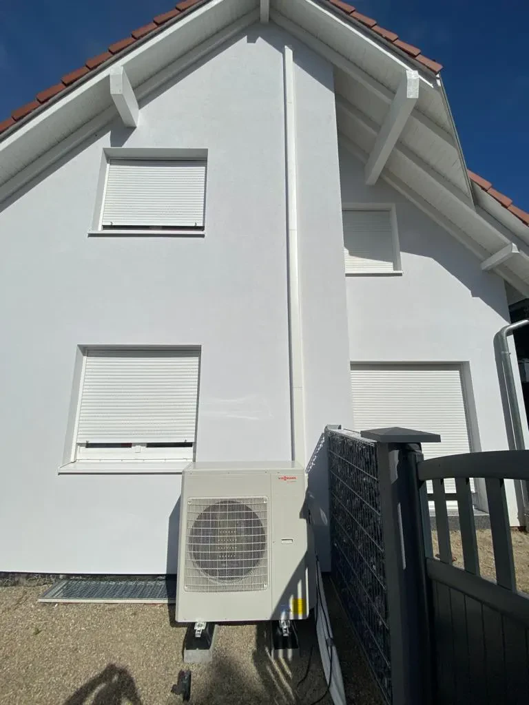 Extérieur d'une maison blanche à deux étages avec volets roulants blancs fermés sur toutes les fenêtres