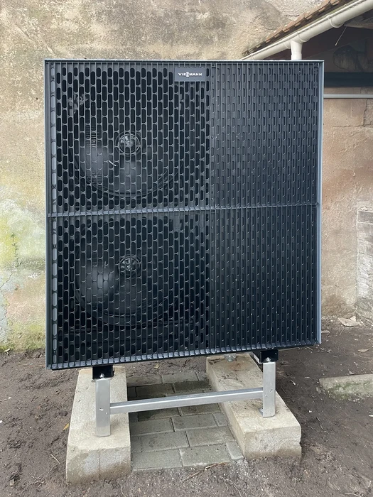 Scène extérieure avec unité de climatisation ou pompe à chaleur installée sur support métallique surélevé