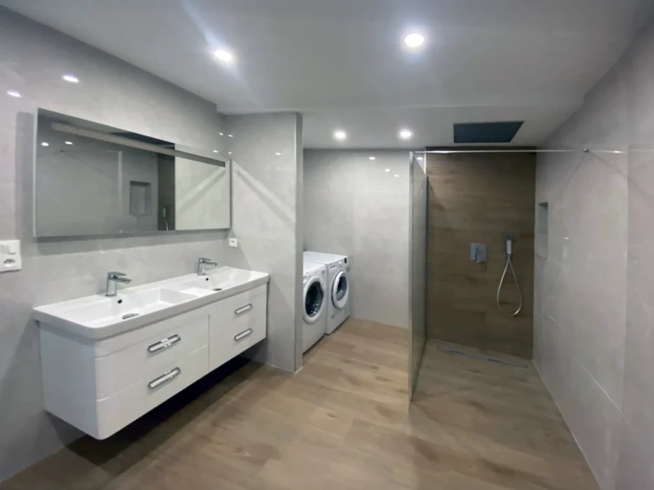 Salle de bain moderne avec douche à l'italienne, double vasque suspendue blanche et espace buanderie intégré