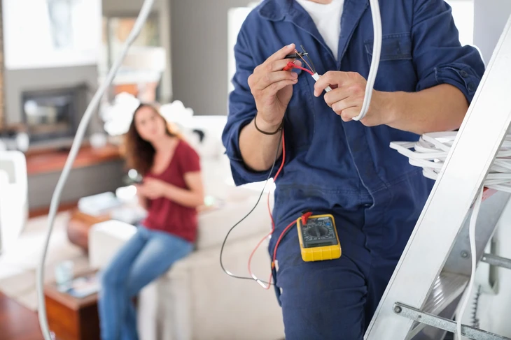 Plombier professionnel en uniforme travaillant dans une salle de bain moderne blanche
