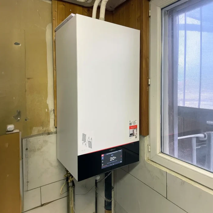 Intérieur en cours de rénovation avec chaudière murale blanche installée près d'une fenêtre