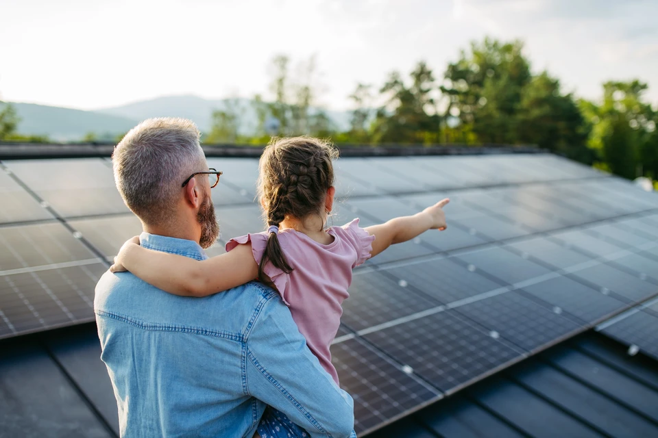 Bonne famille courant près de leur maison avec des panneaux solaires