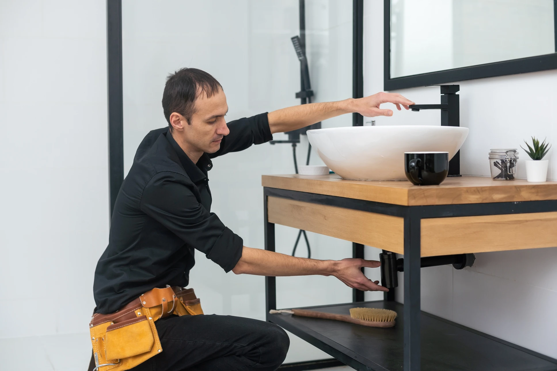 Jeune plombier travaillant avec un spanner dans un système d'installation de lavabo sanitaire